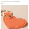 An orange leather heart-shaped keychain is shown against a light background.