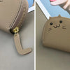 A light beige faux leather wallet with a cartoon cat design and a leather charm.