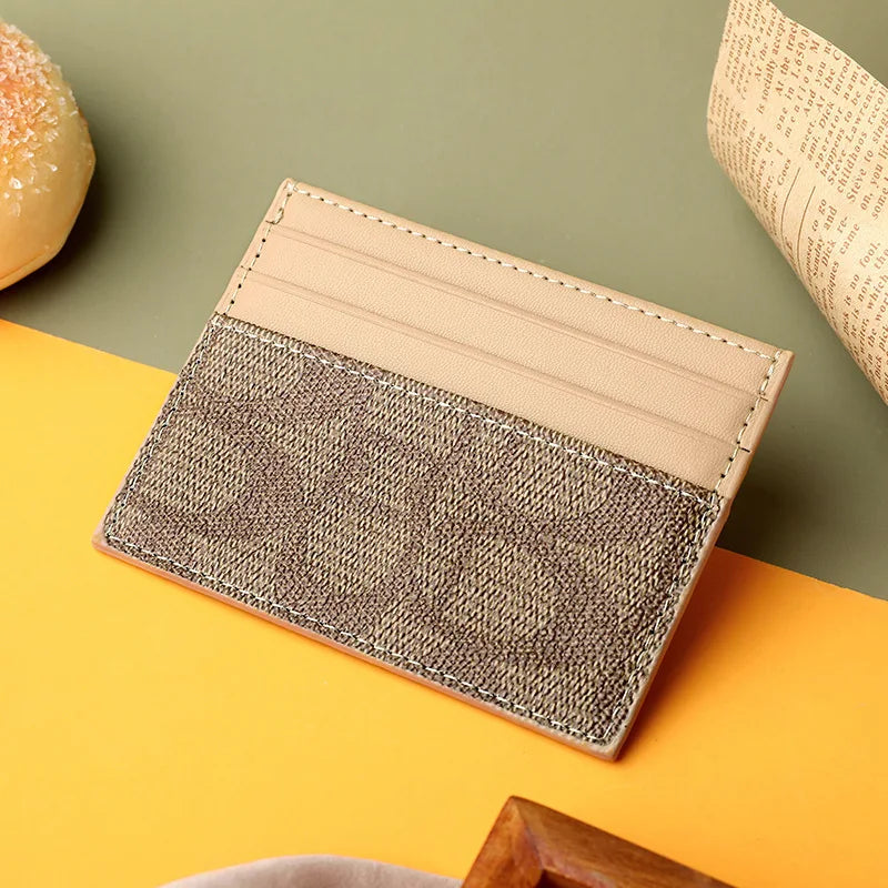 A beige and brown textured PU leather card holder purse resting on an orange surface.