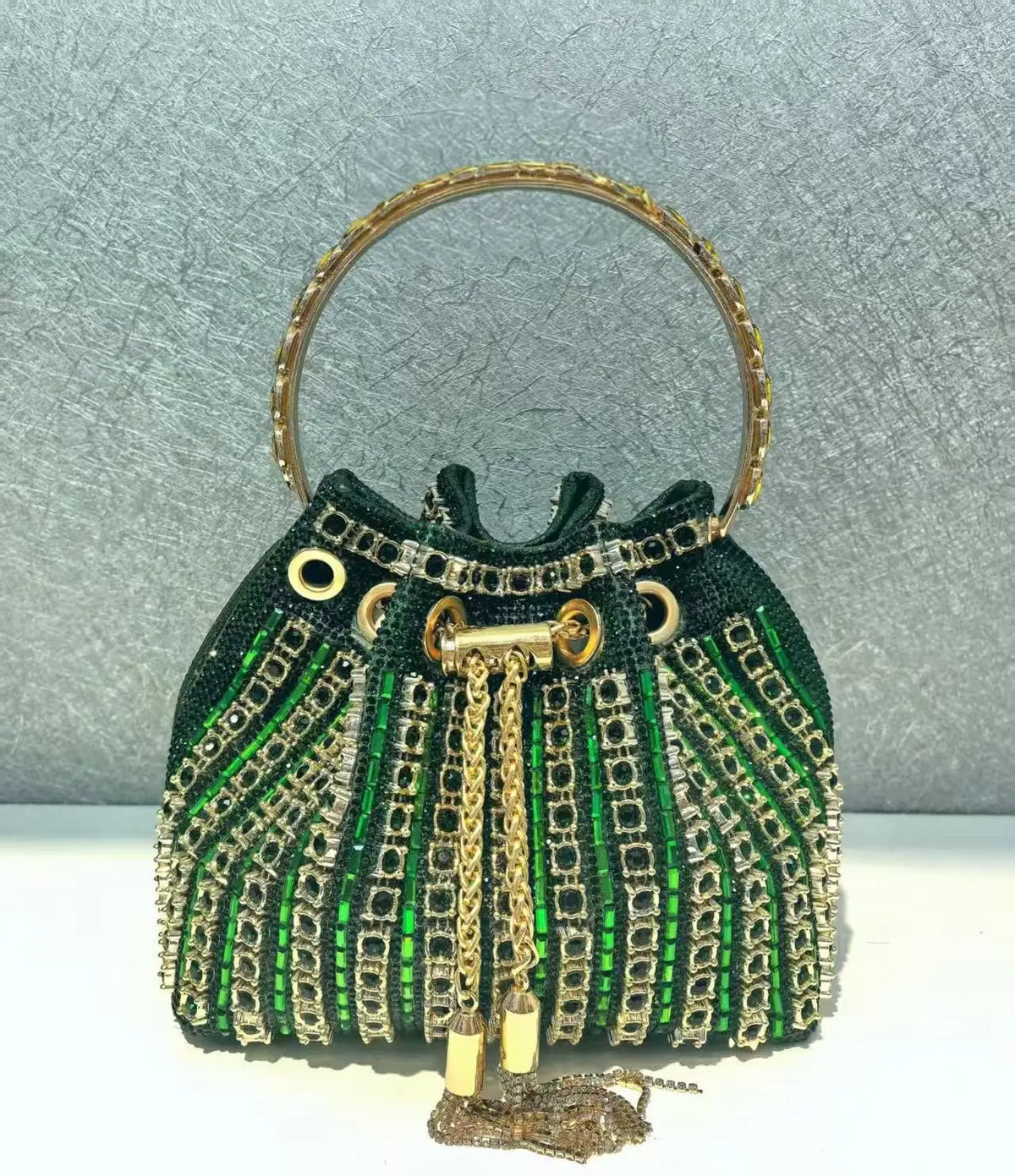 A dark green crystal-embellished evening clutch featuring gold chain detailing and a gold-toned rim.