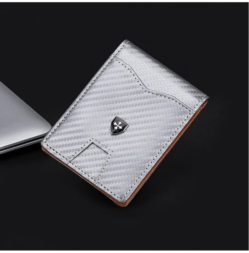 Cartera delgada plateada de fibra de carbono con borde de cuero y emblema metálico.