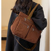 A person is carrying a brown textured corduroy tote bag with adjustable straps over their shoulder.