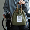 A person holds a olive green waterproof insulated lunch bag with brown drawstrings.