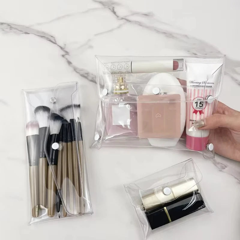 A transparent portable organizer pouch holds makeup brushes, a perfume bottle, and a cosmetic product.