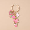 A gold-colored enamel heart keychain featuring a love heart and a pink flower design.