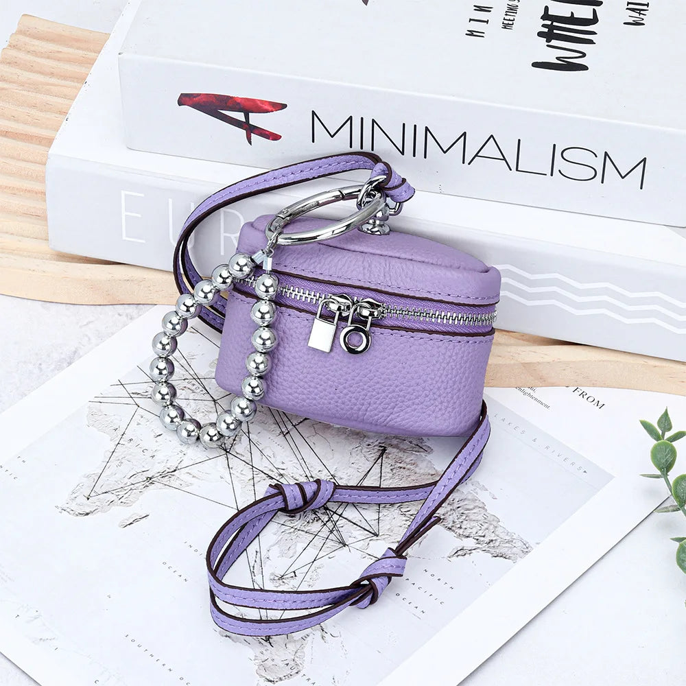A purple handcrafted leather coin purse with a silver chain and lanyard resting on a map.
