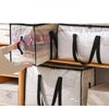 A hand is opening a large transparent woven storage bag with black straps on a wooden shelf.