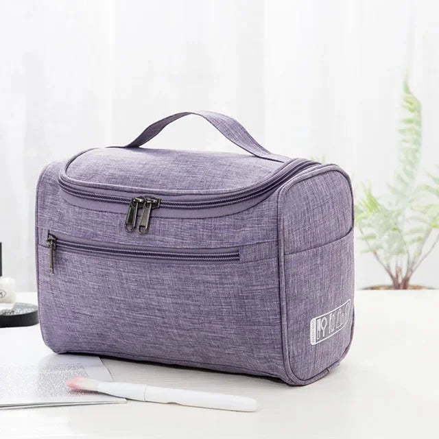 A purple portable Oxford cloth toiletry bag with a zippered compartment is shown on a white surface.