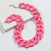 A pink matte acrylic chain necklace with a gold-colored clasp is displayed on a white box.