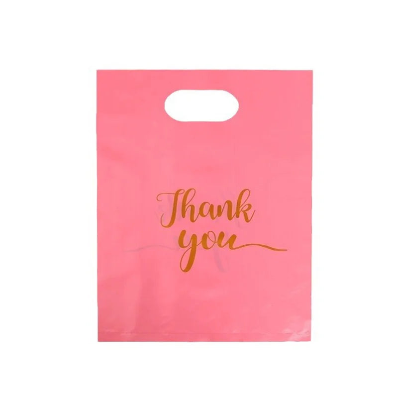 A pink gift bag with gold script writing that says Thank you