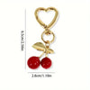 Gold heart-shaped bag charm with a lobster clasp and two red cherry beads