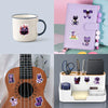 A set of smiling critter stickers featuring various horror-themed cats and other characters on a purple notebook and a guitar