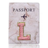 Carátula de pasaporte de cuero marmolado rosa con una inicial L dorada e ícono de avión negro.