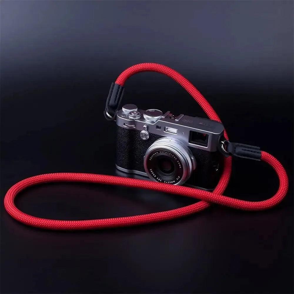 A black camera with a red adjustable strap is shown against a dark background.