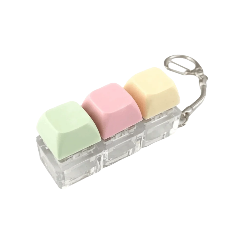 A clear plastic keyboard fidget toy with five pastel colored silicone keys and a metal clip.