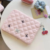 A pink quilted slim laptop sleeve for a MacBook or tablet, resting on a white table.