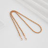 A close-up of a gold-toned braided leather strap with adjustable buckles lying on a white surface.