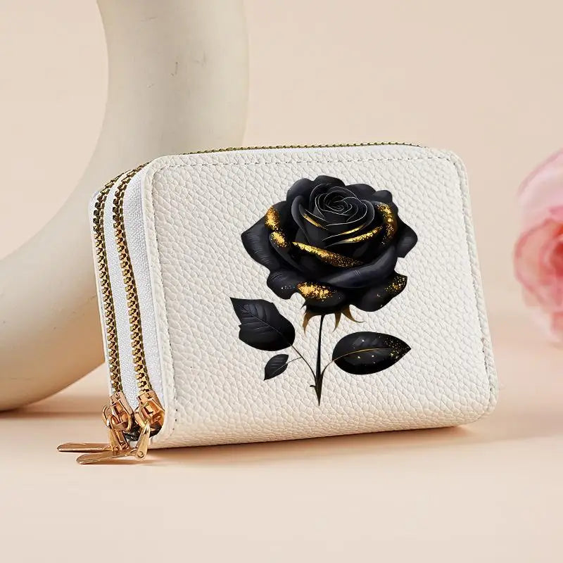 A white zippered wallet featuring a black rose print with gold accents and green leaves.