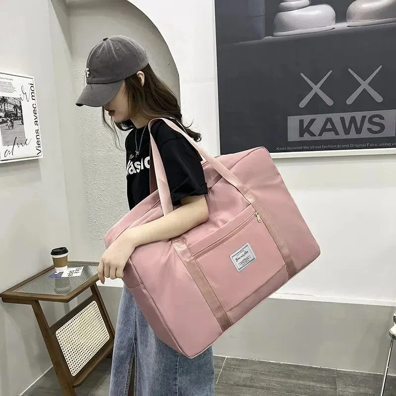 A woman holds a pink canvas travel storage bag with multiple compartments in a modern indoor setting.
