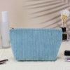 A light blue corduroy makeup organizer bag with an octagonal design resting on a white surface.