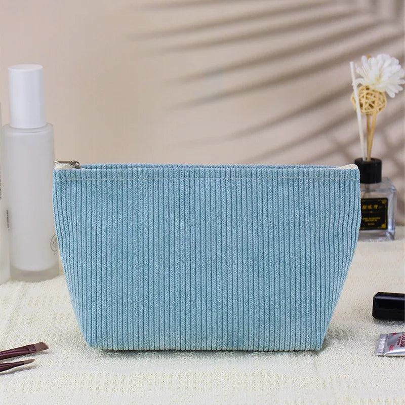 A light blue corduroy makeup organizer bag with an octagonal design resting on a white surface.