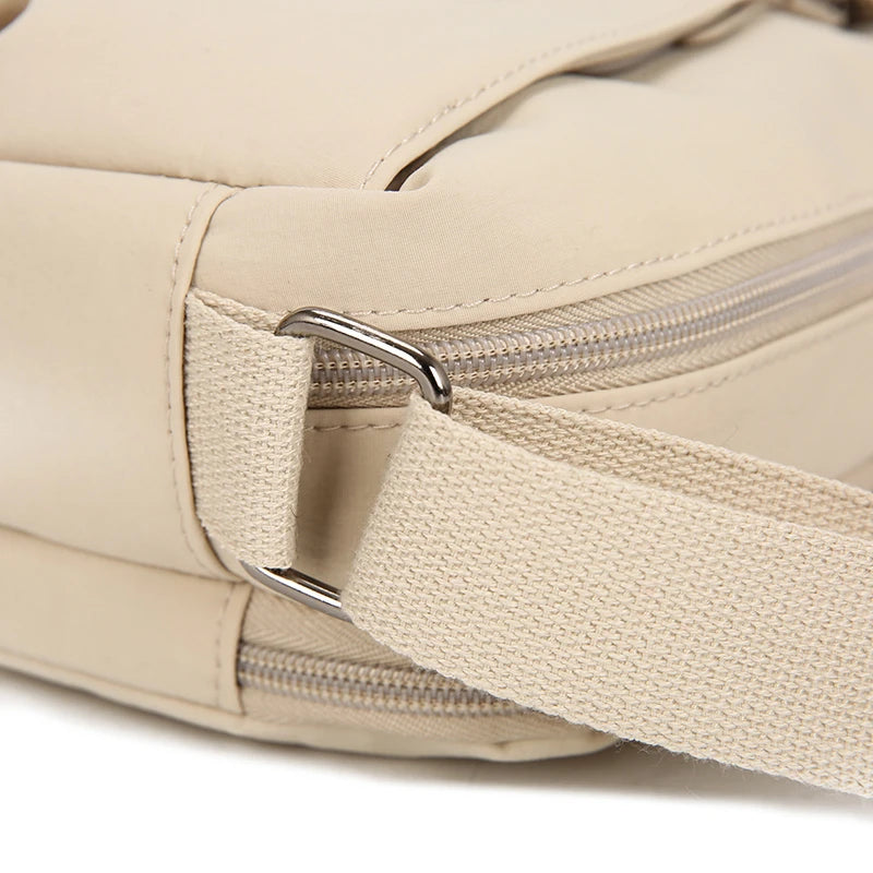 Bolso cruz impermeable de nylon beige con cremallera y correa plateada.