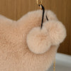 A light beige faux fur heart shaped crossbody purse with a black strap and gold hardware.