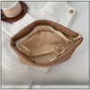 A tan quilted cosmetic travel bag with a gold zipper is shown open on a white textured cloth.