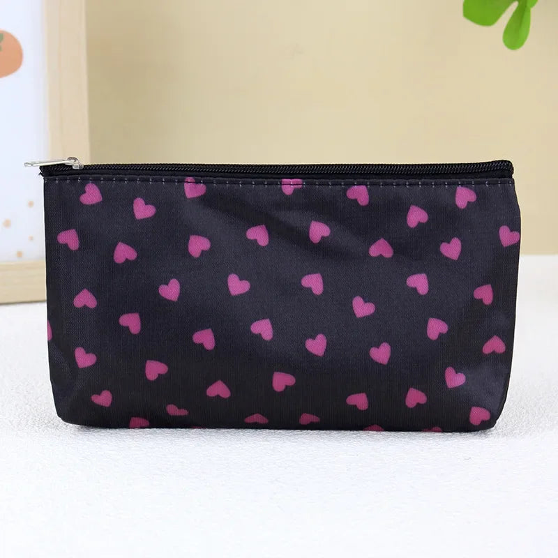 A black zippered cosmetic bag patterned with small pink hearts.