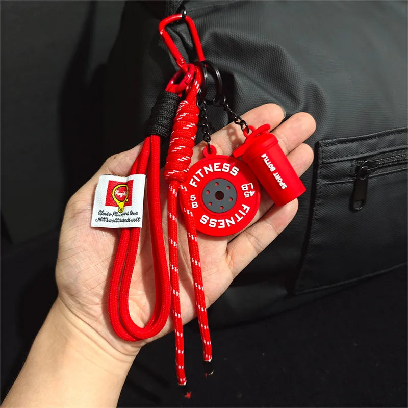 Red D-Shape nylon fitness keychain with a silicone sport bottle attached, held in a hand against a black jacket.