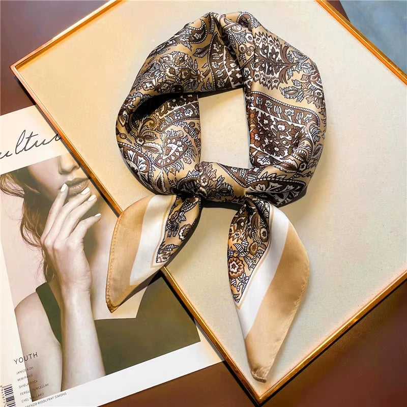 A patterned silk scarf tied in a bow, displayed on a light-colored box next to a magazine photo.