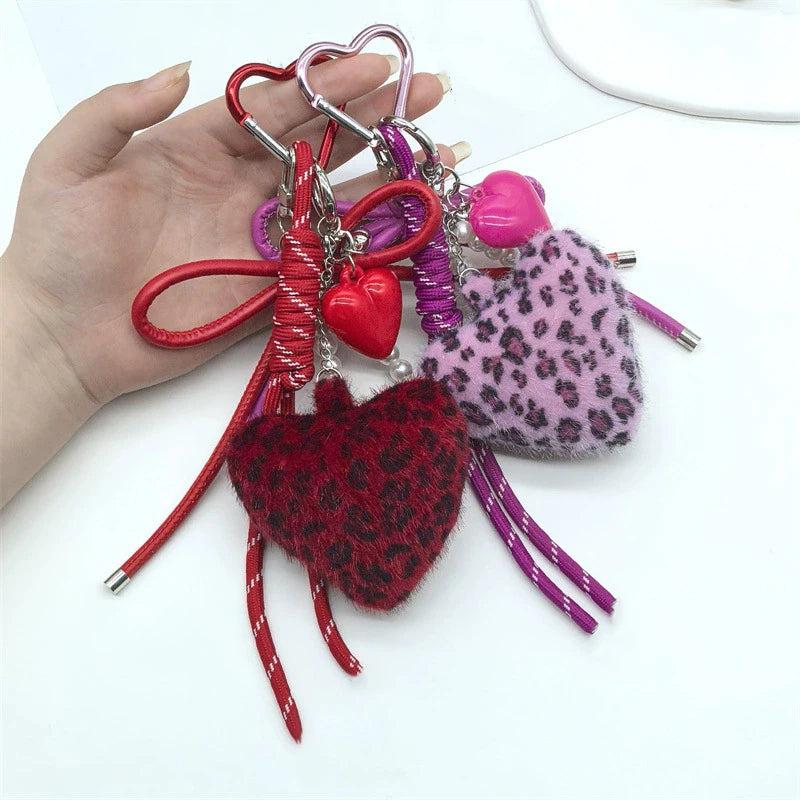 A collection of heart-shaped charm keychains featuring red, pink, and purple leopard print faux fur.