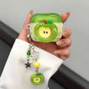 A hand holds a green apple shaped earphone case with a yellow interior and a silver charm necklace.