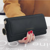 A black waterproof nylon crossbody bag is held by a hand against a light surface.