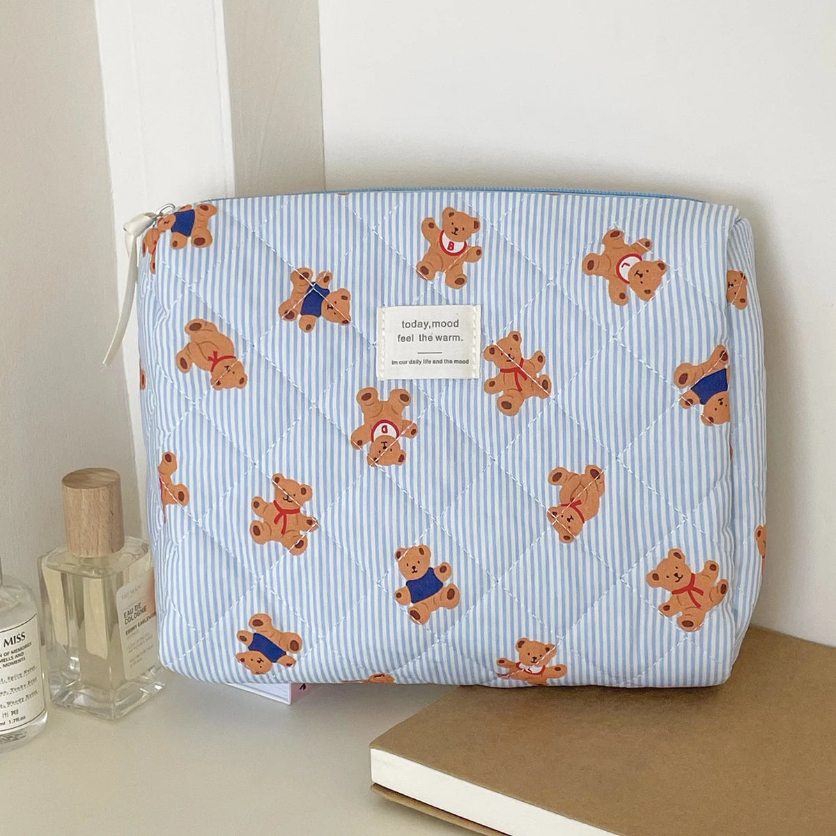 A light blue striped cosmetic makeup bag featuring a pattern of small brown teddy bears.