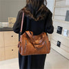 Une femme tient un sac fourre-tout en cuir marron avec plusieurs poches dans un studio.