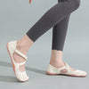 A woman wearing light beige barefoot five-toe shoes with an adjustable strap and dark gray leggings.