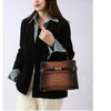 A woman models an elegant brown PU leather shoulder handbag with a dark shirt and black jacket.