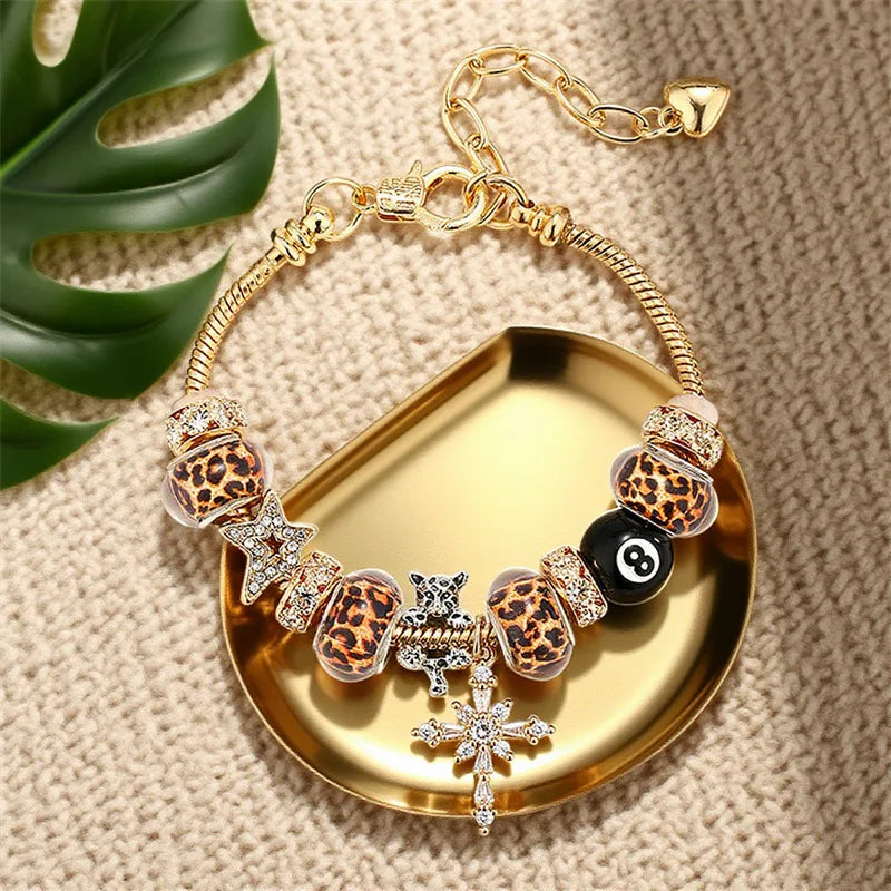 Gold chain bracelet featuring leopard print and black beads displayed on a gold tray