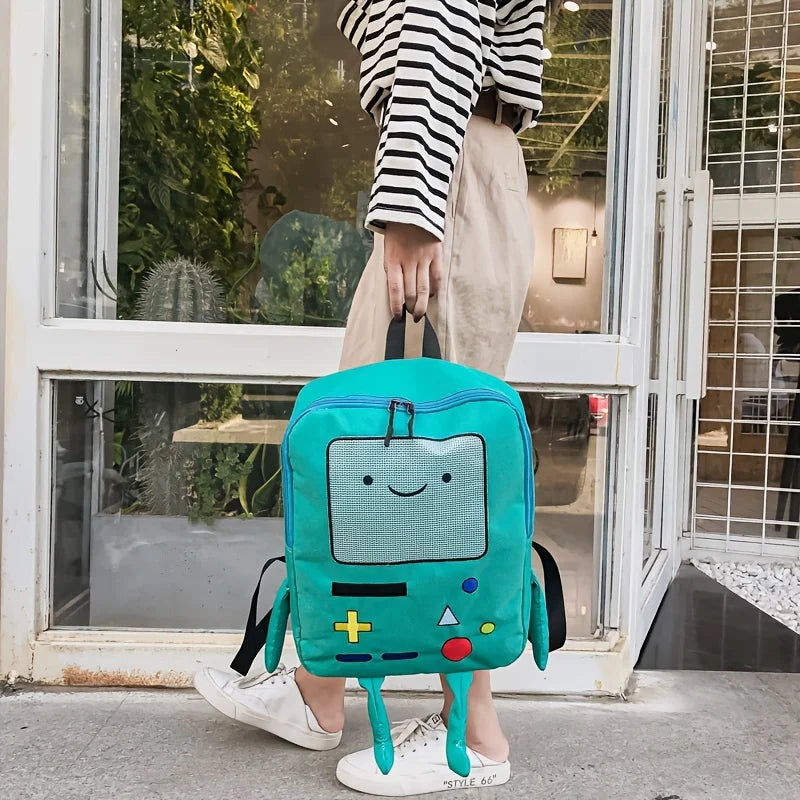 A teal cartoon robot backpack is displayed in front of a glass door, worn by a person in striped shirt and light pants.