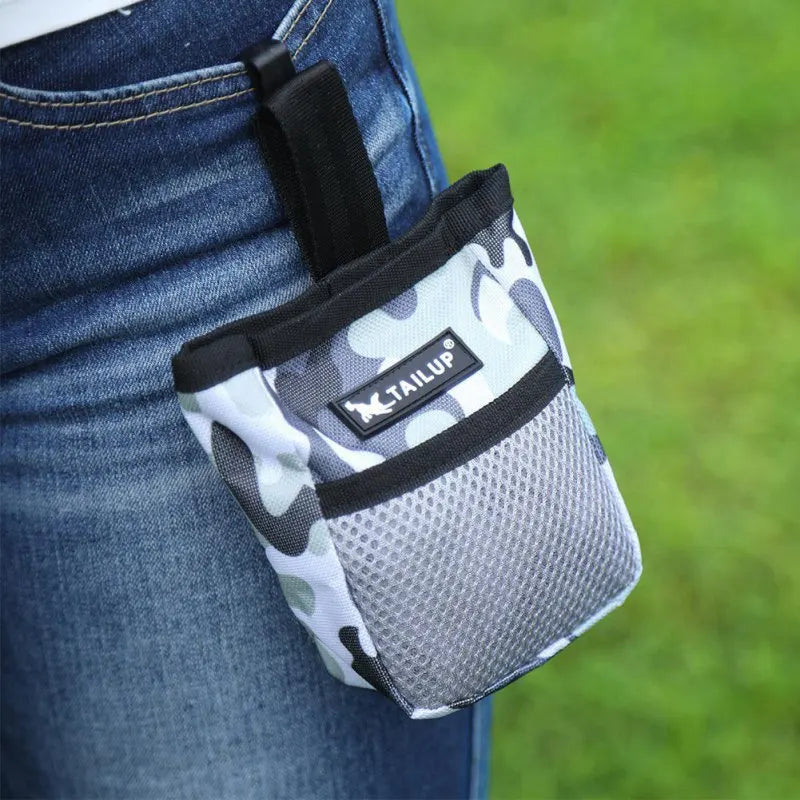 A black and white camouflage pet training treat pouch attached to a pair of blue jeans.