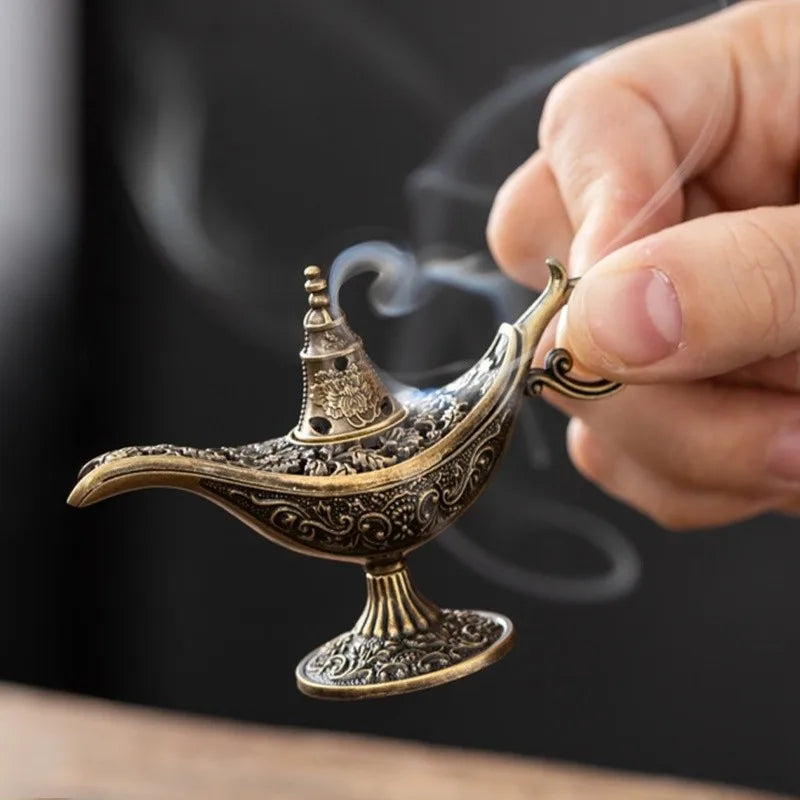 A hand holds an antique metal incense burner, releasing smoke against a dark background.
