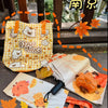 A collection of cute maple leaf plush keychain bags and charms displayed on a wooden surface.
