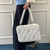 Una mujer sostiene un bolso de ordenador portátil acolchado blanco con detalles de lazo azul.