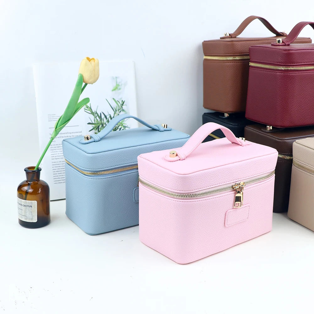 A collection of customizable PU leather makeup bags in various shades of pink, brown, and blue, next to a yellow rose.