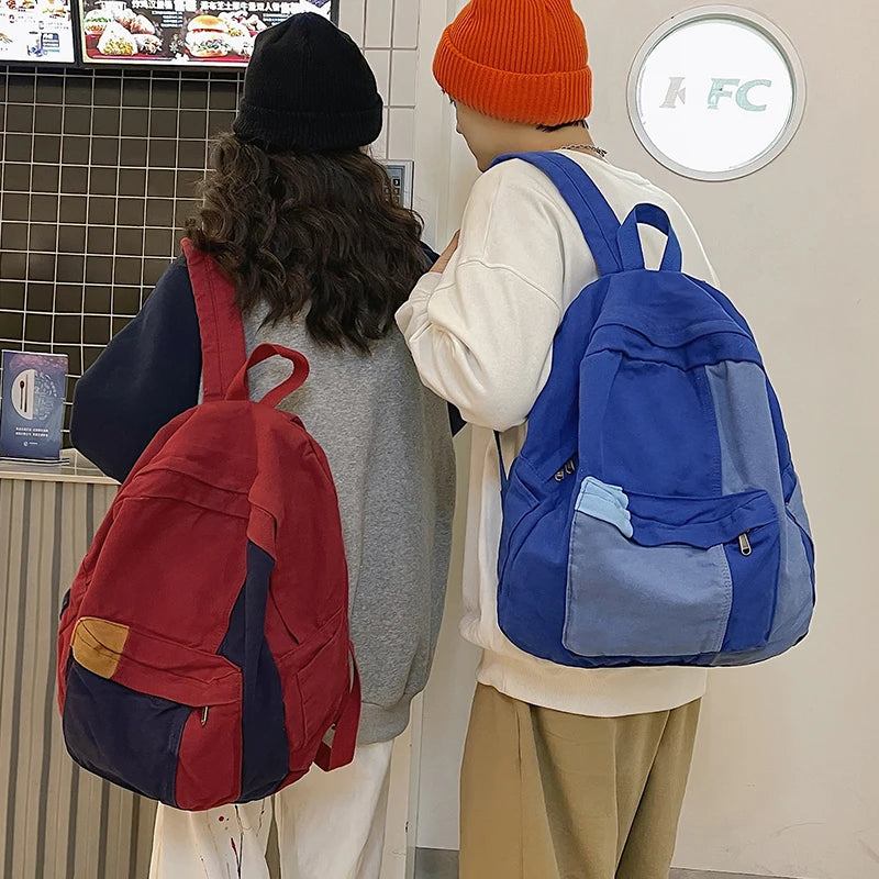 A person wearing a white top and orange beanie is holding a blue backpack while another person with long dark hair is carryin
