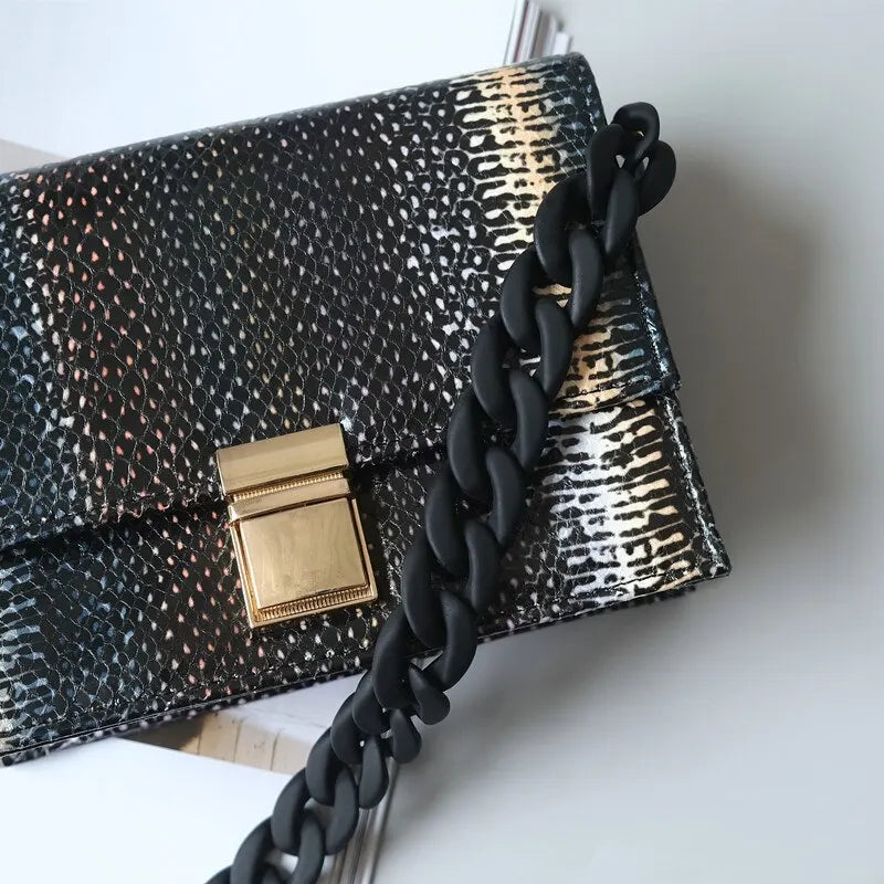 A black and gold patterned clutch or bag with a thick black braided strap.