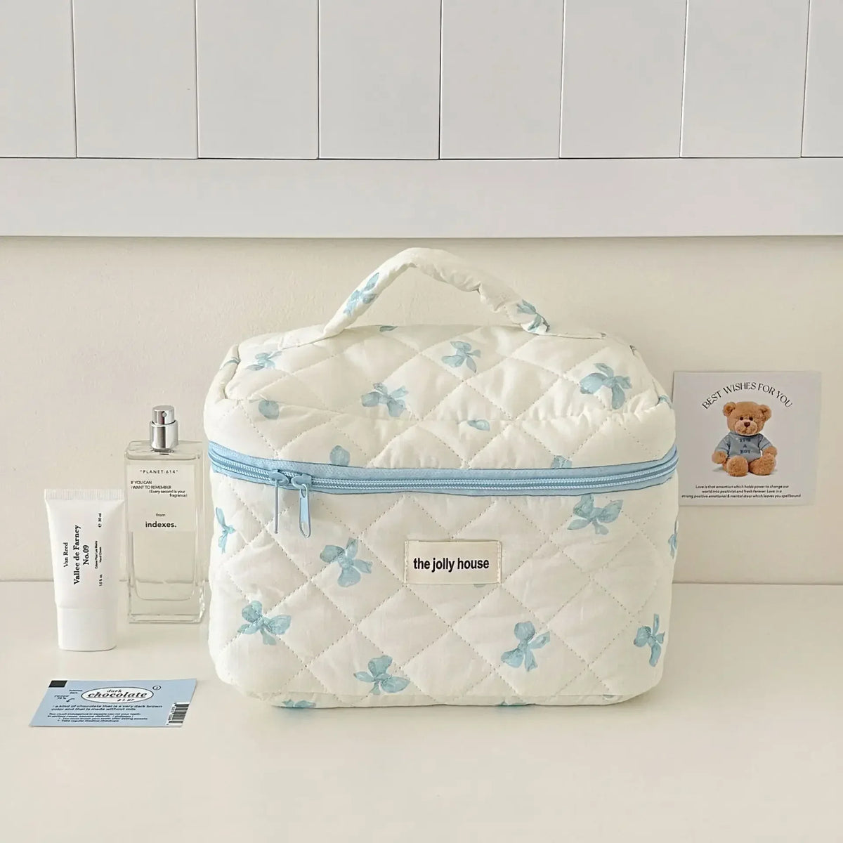 Sac de rangement cosmétique en rembourrage blanc avec motif de nœud bleu sur une surface claire.