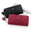 A deep red quilted clutch wallet with gold chain detail resting on a white background next to some paper.