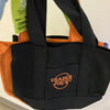 A black canvas bag with an orange strap and a Trader Joe's logo on the front.